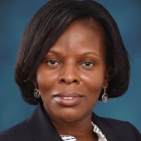 Photo of Judith Owour smiling in front of a blue background